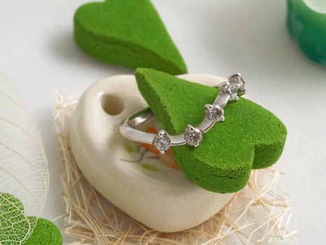 Gift a set of aromas green color in the form of heart with diamond ring isolated on white