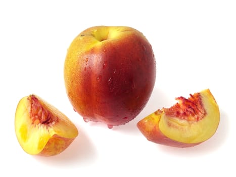 Tasty juicy pieces of nectarine on a white background with water droplets