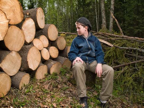 A boy sitting near the prepared logs