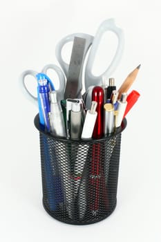 Black metal pencil cup filled with colorful used pencils, pens and scissors, isolated