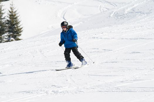 Boy skiing down a snowy slope on a sunny day