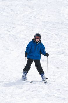 Smiling boy on skis at bottom of ski slope