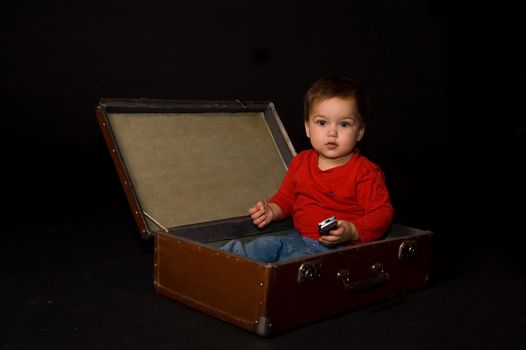 Surprised boy holding phone in luggage
