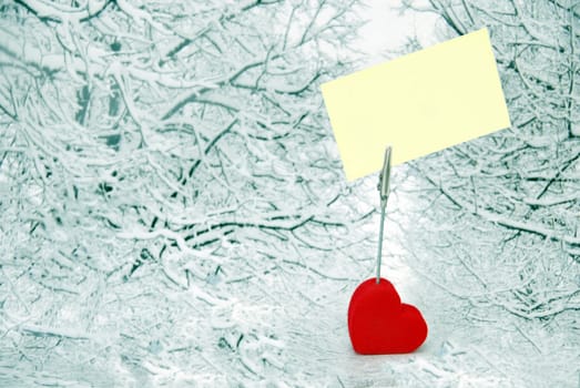 heart shape holder of paper with blank visit card over winter snowy background