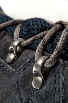 Close up capturing the laces on a dark blue walking boot with white background.
