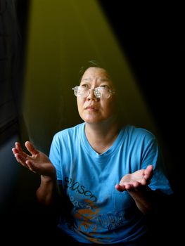 a Asian woman is praying and a golden light sine on her