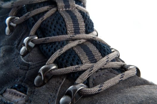 Close up, low level angle capturing the laces on a dark blue walking boot with white background.