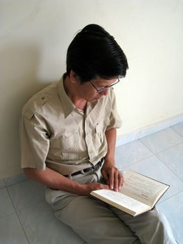 a Asian man is reading a book