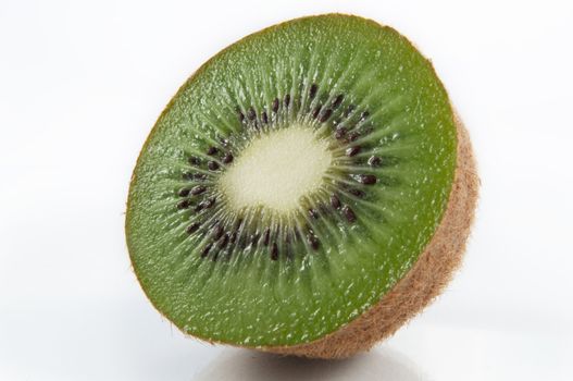 Close up and low level capturing half a freshly cut kiwifruit arranged over white.