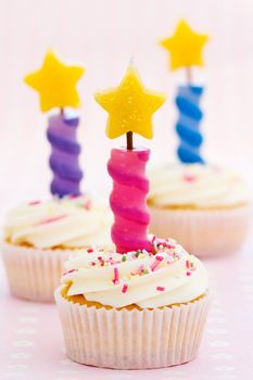 Three cupcakes decorated with colorful birthday candles