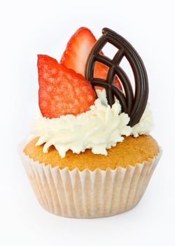 Cupcake decorated with strawberries, cream and a chocolate leaf