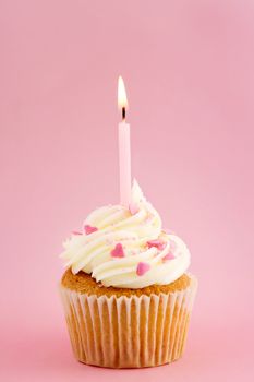 Cupcake decorated with pink sprinkles and a single candle