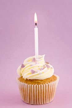 Cupcake decorated with purple sprinkles and a single candle