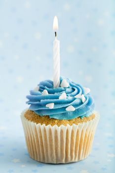 Cupcake decorated with blue frosting and a single candle