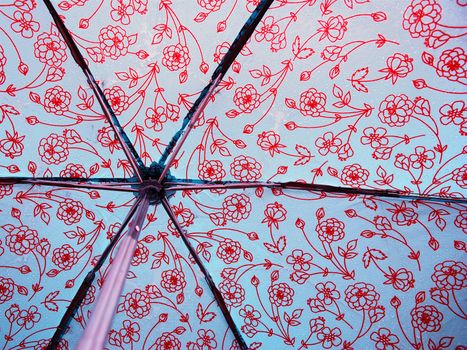 A photograph of the inside of an opened umbrella covered in raindrops