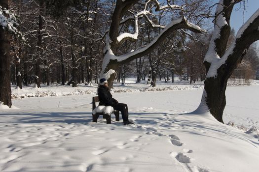 Man on the bench. Relax in the winter in park