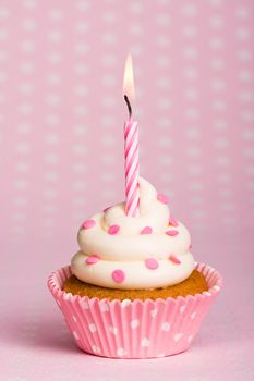 Spotty pink cupcake with a stripey candle