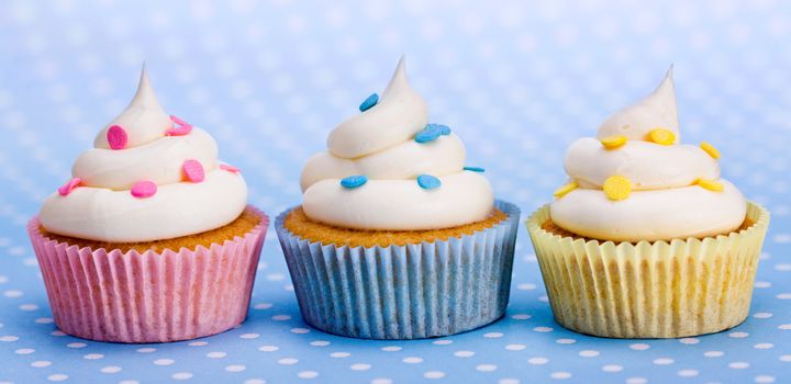 Pink, blue and yellow cupcakes in a row