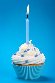 Cupcake with a single blue candle, decorated with sugar stars