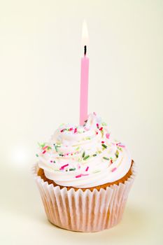 Cupcake decorated with sugar sprinkles and a single candle