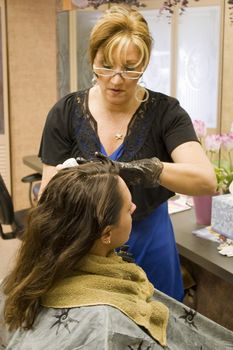 A hairdresser working on a clients hair color at the salon.