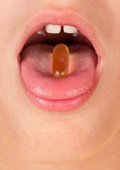 boys mouth with pill or capsule on tongue