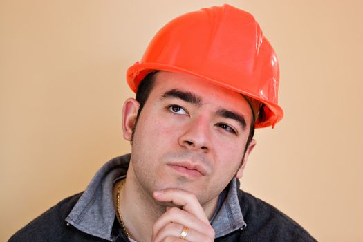A young construction working with a pensive or contemplative look thinking hard about something.