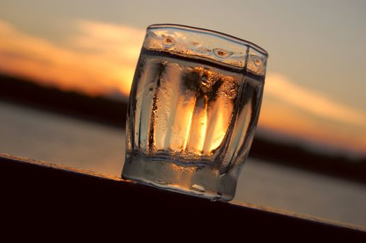 Deep in russian soul. Russian nostalgia.
Close-up of glass of cold vodka against colorful sunset (on rail of yacht sailing Volga-river)