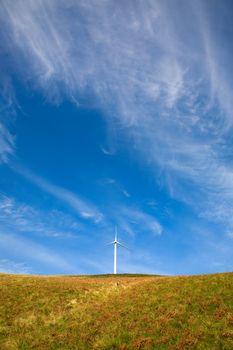 Wind tower on a field with blue sky.