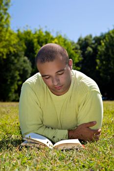 Young man, reading, in an outdoor park.