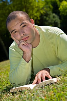 Young man, reading, in an outdoor park.