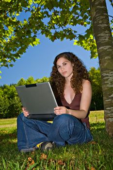 A beautiful young girl, using her laptop on a park.