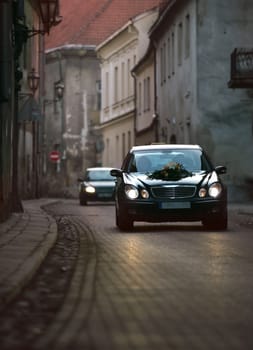 Two wedding automobiles in narrow street of old city