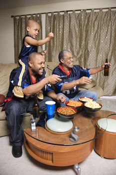 Three male generations of an African-American family watching football game on tv.