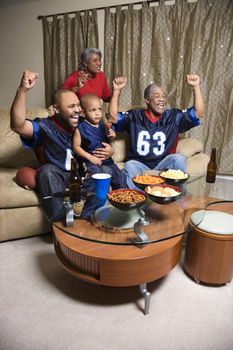 A three generation African-American family cheering and watching football game together on tv.