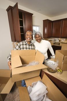 Portrait of middle-aged African-American couple with moving boxes in kitchen.