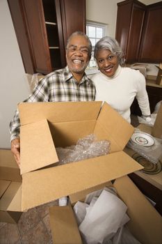 Portrait of middle-aged African-American couple with moving boxes in kitchen.
