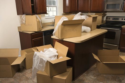 Cardboard moving boxes with bubble wrap in kitchen.