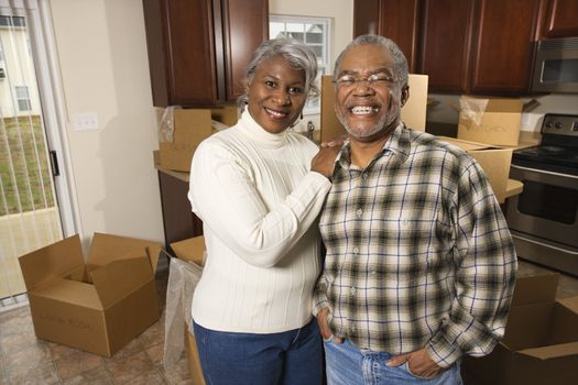 Portrait of middle-aged African-American couple in kitchen with moving boxes.