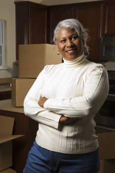 Portrait of middle-aged African-American female in kitchen with moving boxes.