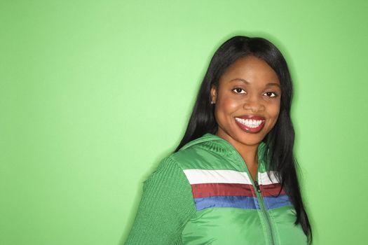 Smiling African-American mid-adult woman in green coat on green background.