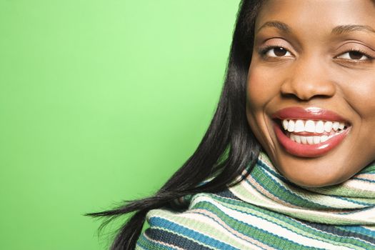 Smiling African-American mid-adult woman wearing green scarf on green background.