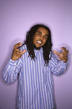 Smiling African-American mid-adult man on purple background with hands gesturing.