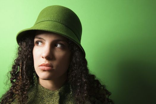 Young Caucasian woman on green background wearing green clothing and hat.