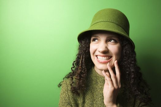 Smiling young Caucasian woman on green background wearing green clothing and hat.