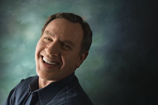 Laughing middle-aged Caucasian man on studio background.