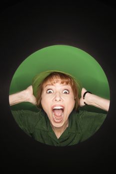 Vignette of Caucasian mid-adult woman with surprised expression wearing hat on green background.