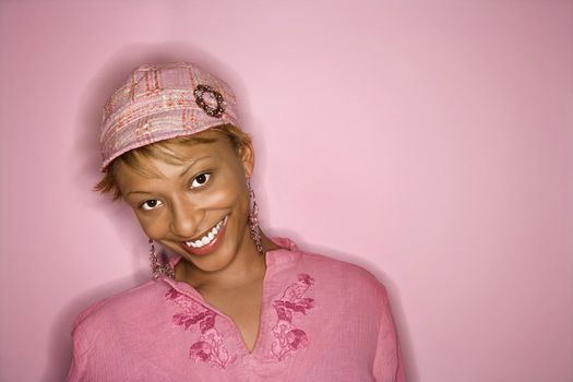 Portrait of smiling African- American young adult woman on pink background.
