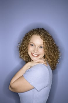 Portrait of smiling young adult Caucasian woman on blue background.