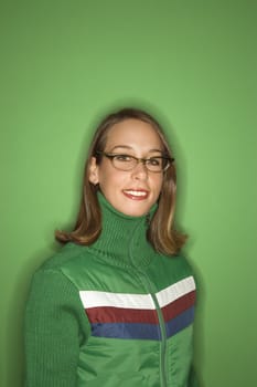 Portrait of smiling young adult Caucasian woman on green background wearing winter coat.